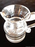 Top view of clear glass creamer showing spout, handle and ribbed base