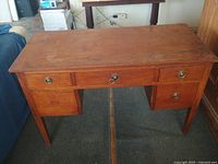 Front view of solid maple kneehole desk showing five drawers and brass-tone pulls