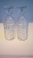 Both pressed glass decanters side by side with stoppers in place showing pattern and clarity