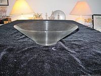 Side profile of clear ribbed glass bowl on black fabric