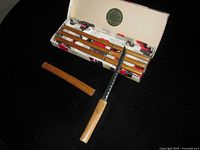 Open box showing four knives with sheaths, one knife unsheathed