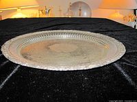 Top view of round silver plate salver tray on black cloth