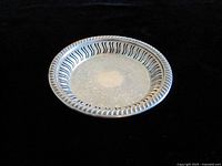 Top view of round silver plate wine coaster showing slotted gallery and engraved center