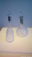 Two cut crystal decanters with silver-plated collars and stoppers displayed side by side