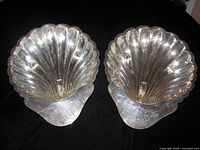 Front view of both silver-plated scallop shell dishes showing fluted interiors and footed bases