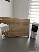 Wooden charcuterie board laying flat on surface showing full length and smooth wood finish with unique handle shape and hole.