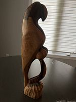 Side view of hand-carved wooden parrot sculpture showing smooth finish and natural wood tones.