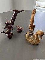 Photo showing the entire collection of five wooden birds including the three mahogany birds on a single base, a pelican, a standing carved bird, and a decoy duck.