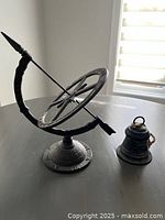 Full view of nautical compass and metal bell on table