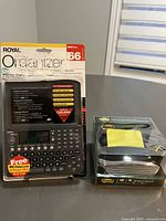 Photo of Royal DM80ex personal organizer in original packaging showing features and front view with LCD screen and keyboard.