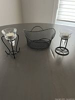 Six black metal mesh snack baskets and two black metal tealight holders displayed on a table.
