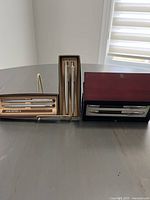 Three pen and pencil sets displayed on table, two Sheaffer sets and one Parker set