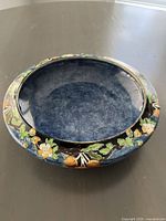 Topside angled view showing the deep interior blue color and the painted rim with floral and fruit motifs.