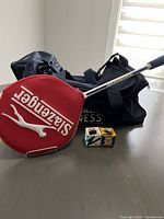 Squash racquet with red Slazenger cover, GoodLife Fitness bag, and two squash balls.