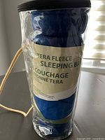 Blue Terra Gear fleece sleeping bag rolled and packed in plastic with label visible.