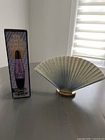 Both lamps shown on table against white wall and window, highlighting pale blue fan shade and glitter lamp body