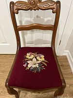 Full view of wooden chair showing burgundy needlepoint floral seat upholstery