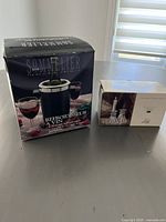 Photo of boxed Sommelier wine chiller and boxed set of Cristal d'Arques crystal candle holders on shelf with window light.