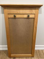 Front view of wooden calendar holder showing light wood frame with MDF center panel and two knobs for hanging.