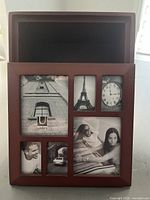 Front view of brown wooden collage frame with 7 photo openings featuring black and white sample photos showing architecture, clock, and people.