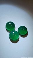 Photo showing three round green onyx cabochon gemstones with smooth surfaces and deep green color.