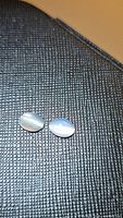 Pair of oval natural cabochon moonstones with visible catseye band on black textured background under lighting to show catseye effect.