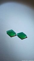 Pair of two polished green onyx gemstones with fancy cut shapes, shown on white background.