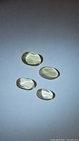 Four oval cabochon lemon citrine gemstones viewed from top side, showing color, cut and clarity under natural light.