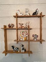 Full view of wooden wall shelf holding the animal figurines including cats, elephants, and deer, showcasing layout and approximate size.