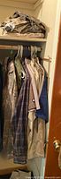 Closet with hanging assorted camouflage jackets and work shirts including plaids