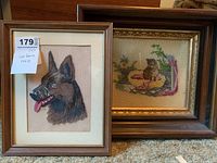 Photo showing both framed petit point artworks featuring a dog and a cat together.