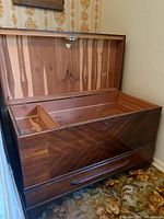 Opened wooden cedar lined chest with dark wood veneer exterior and internal divider compartment.