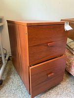 Photo shows full wooden file cabinet with two drawers, one partially open showing drawer front and sides.