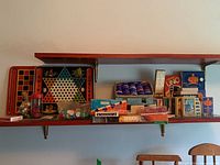 Wide view of shelf showing vintage metal game boards, bags of poker chips, and boxed card games including Uno