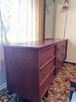Side view of dresser showing three left-side drawers, wood veneer finish and tapered leg