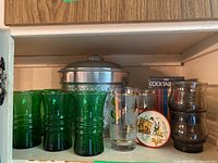 Green mid century modern glasses, clear gold cocktail glass, vintage coasters, metal ice bucket with rim visible