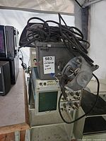 Full view of the oscilloscope unit placed on a metal stand with coiled cables on top and power supply underneath. Label on stand reads 'oscilloscope light & more'.