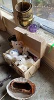 Photo of brass plant pots, glass flower frogs and plush toys in decorative box