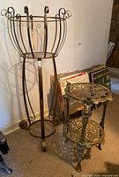 Photo showing the tall basket-style brass plant stand and the shorter two-tier brass plant stand side by side.