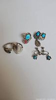 Photo showing three rings and two pairs of earrings, stones turquoise and coral, some pieces missing stones.