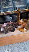 Wide shot of all three carnival glass art pieces showing vase, pedestal candy bowl, and iridescent holly bowl together on a shelf
