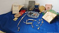 Overview of entire lot items arranged on blue fabric including jewelry, tools, boxes, and accessories