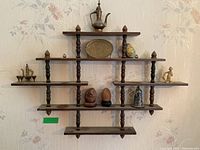 Full view of wooden wall shelf mounted on wallpapered wall showing all displayed items.