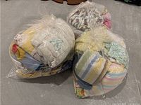 Three large plastic bags filled with assorted baby blankets, various colors and designs visible through bags.