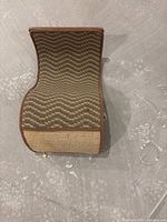 Top view of the curved cat scratcher showing woven zigzag texture and brown fabric edges.