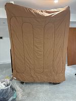 Photo of unfolded brown double sleeping bag showing quilted pattern and size roughly covering a couch or floor area.
