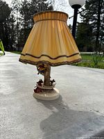 Full side view of Hummel "Out of Danger" lamp with shade outdoors showing figurine base and lamp shade details