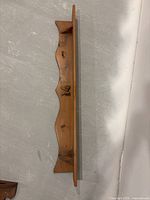 Top view of the wooden bow shelf showing the curved front with three metal hooks and flat top shelf