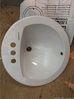 Photo of the round white porcelain sink with three pre-drilled holes and overflow hole, showing a shiny new condition.