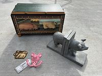Decorative wooden box with pig and cow paintings, showing top and front detail, with pig bookends and pig hooks in front.